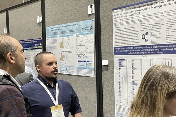 Our Employee, Kyle, presenting a poster at SITC to another scientist 