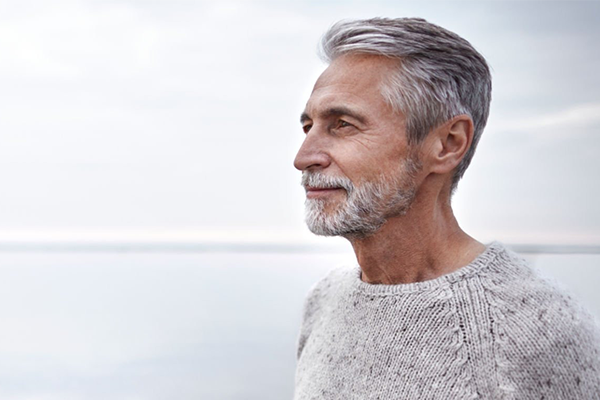Man standing by the sea. He is looking off into the distance