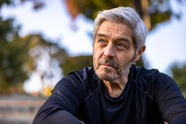 A senior man smiling outdoors at a workout